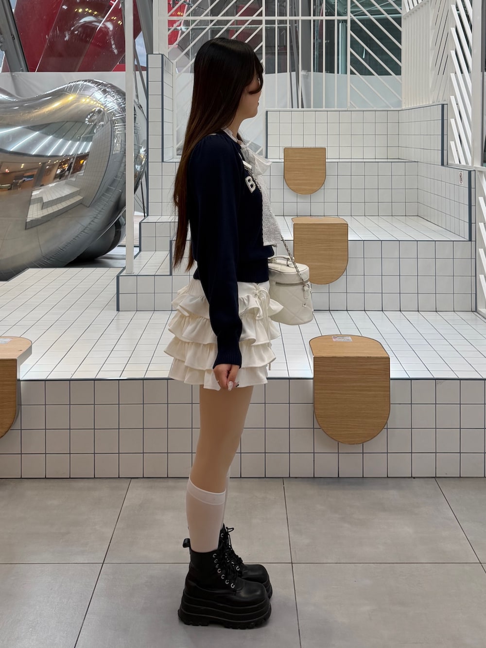 ブルー系のニット/セーター、ホワイト系のスカート、ホワイト系のハンドバッグを着用したレディースの冬コーディネートの3枚目の写真