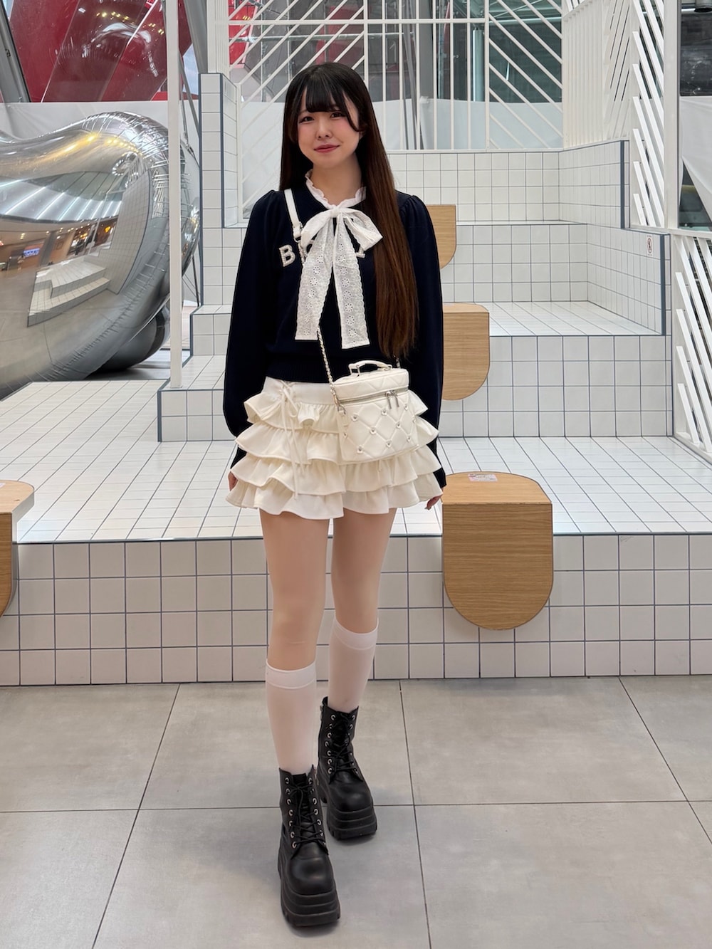 ブルー系のニット/セーター、ホワイト系のスカート、ホワイト系のハンドバッグを着用したレディースの冬コーディネートの2枚目の写真