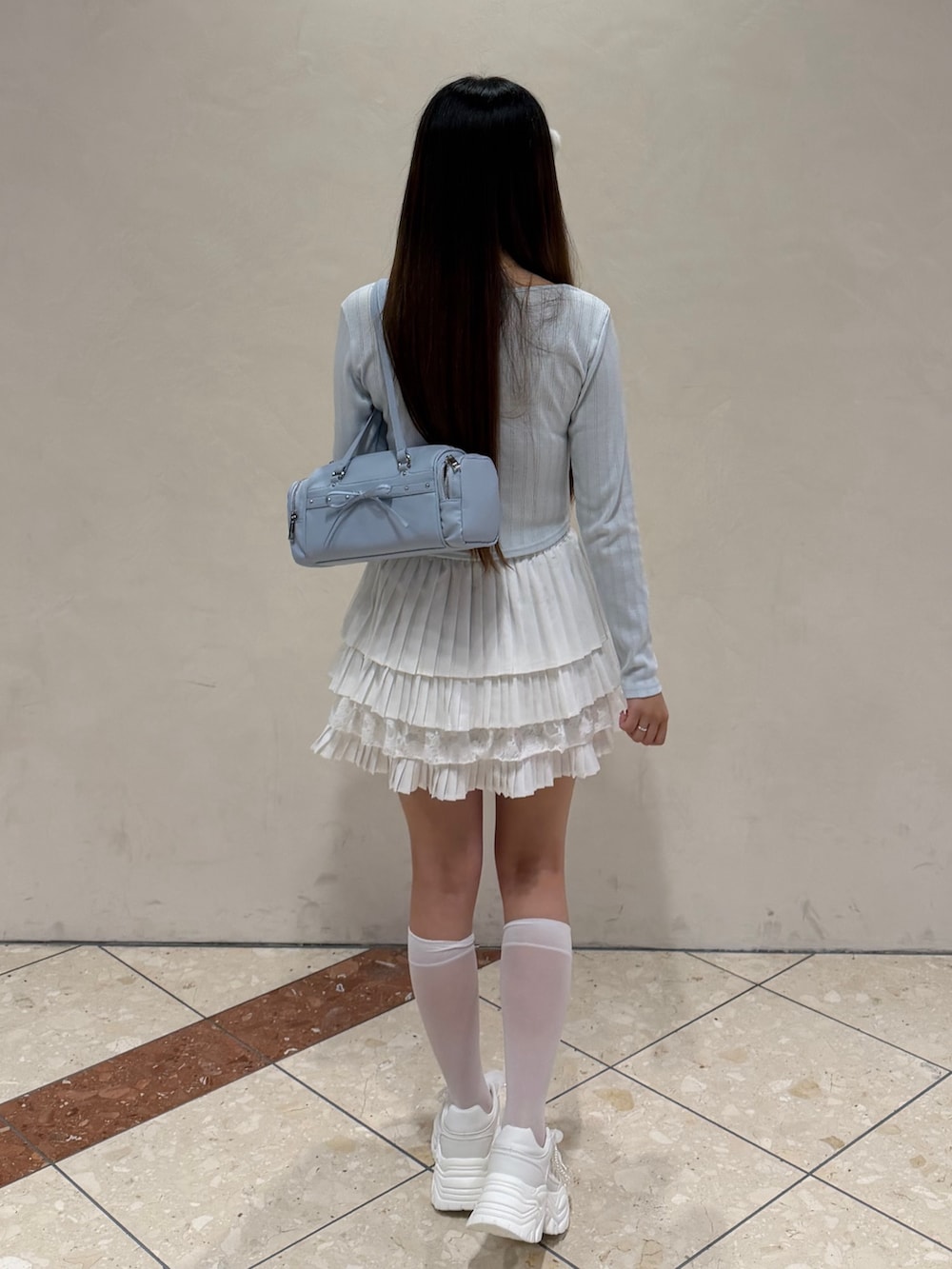 ブルー系のTシャツ/カットソー、ホワイト系のスカート、ホワイト系のスニーカーを着用したレディースの冬コーディネートの4枚目の写真