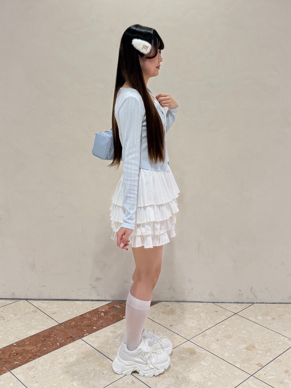 ブルー系のTシャツ/カットソー、ホワイト系のスカート、ホワイト系のスニーカーを着用したレディースの冬コーディネートの5枚目の写真