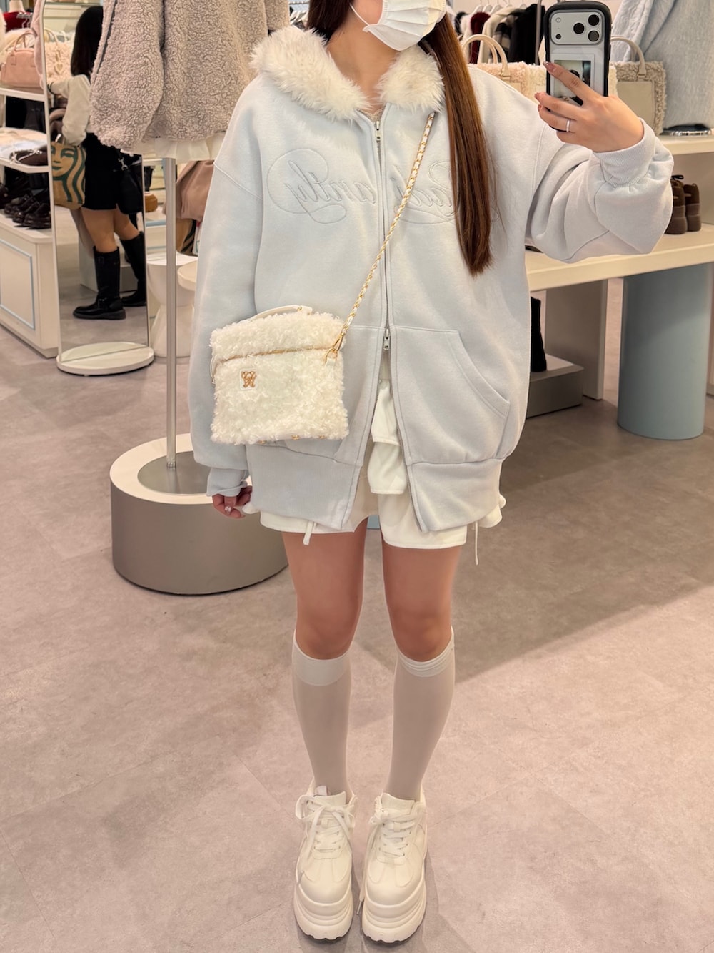 ブルー系のパーカー、ホワイト系のショルダーバッグ、ホワイト系のスカートを着用したレディースの冬コーディネートの3枚目の写真