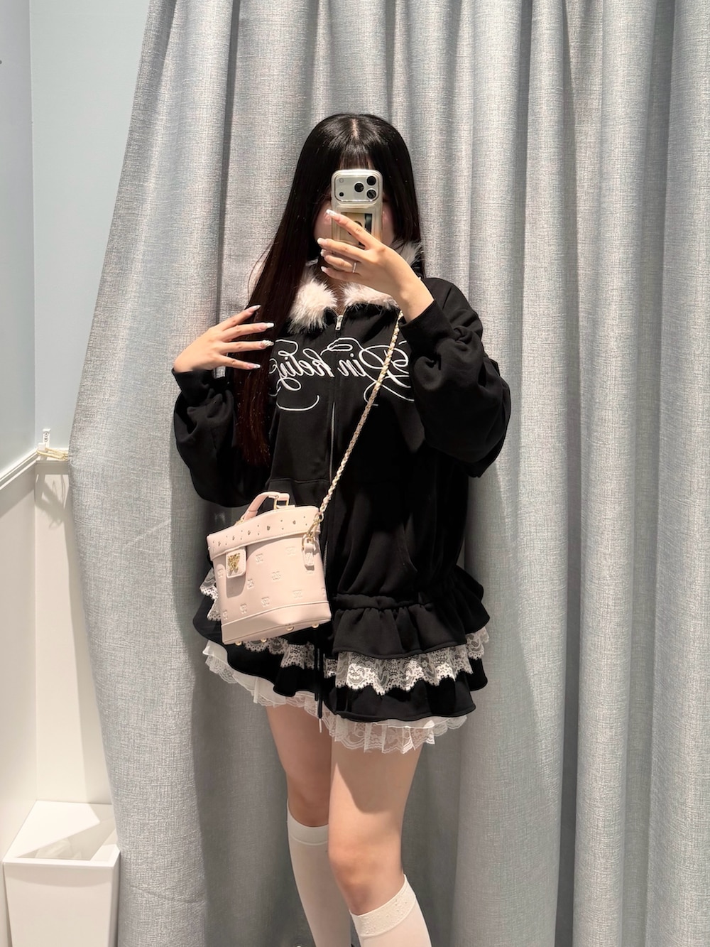 ブラック系のパーカー、ホワイト系のスカート、ピンク系のショルダーバッグを着用したレディースの秋コーディネートの2枚目の写真