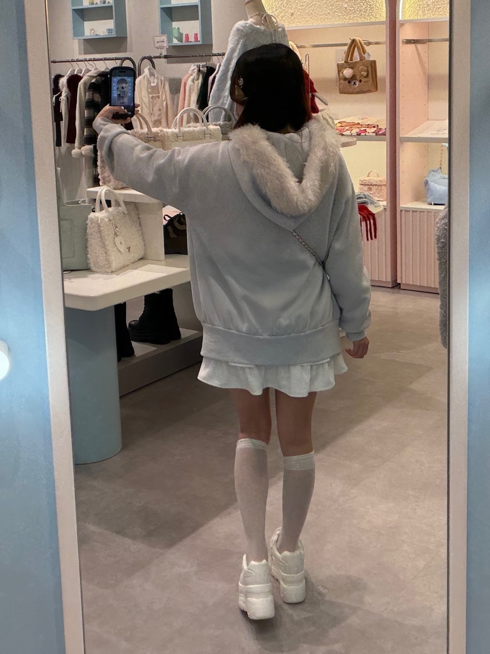 ブルー系のパーカー、ホワイト系のショルダーバッグ、ホワイト系のスカートを着用したレディースの冬コーディネートの4枚目の写真