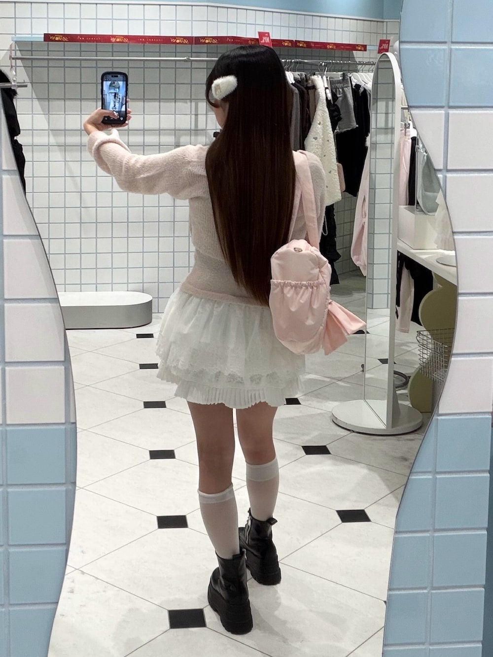 ピンク系のアンサンブル、ホワイト系のスカート、ピンク系のボストンバッグを着用したレディースの冬コーディネートの3枚目の写真