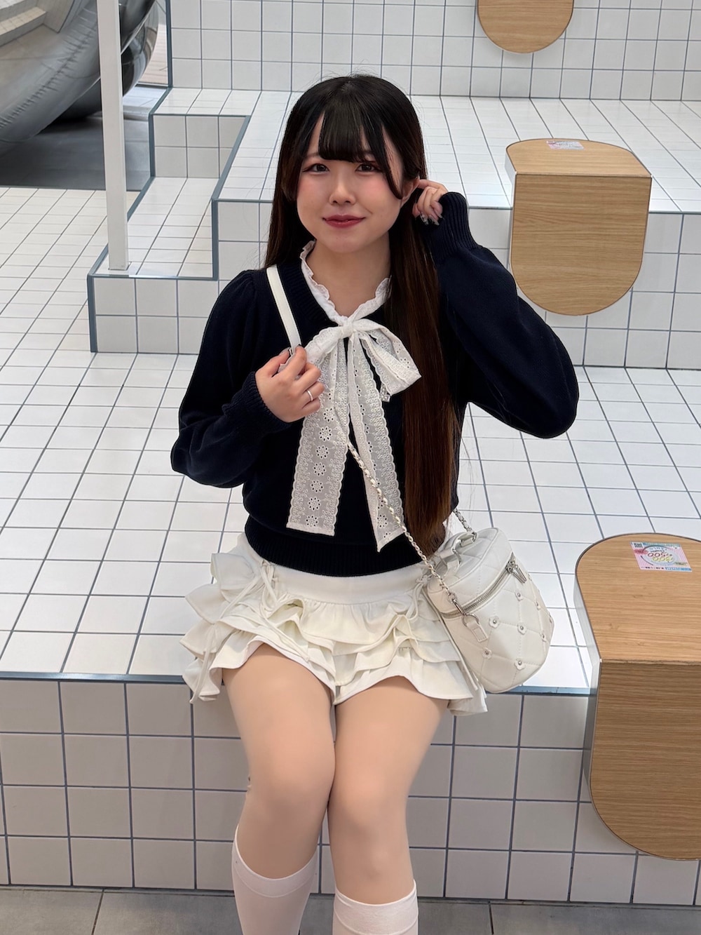 ブルー系のニット/セーター、ホワイト系のスカート、ホワイト系のハンドバッグを着用したレディースの冬コーディネートの6枚目の写真