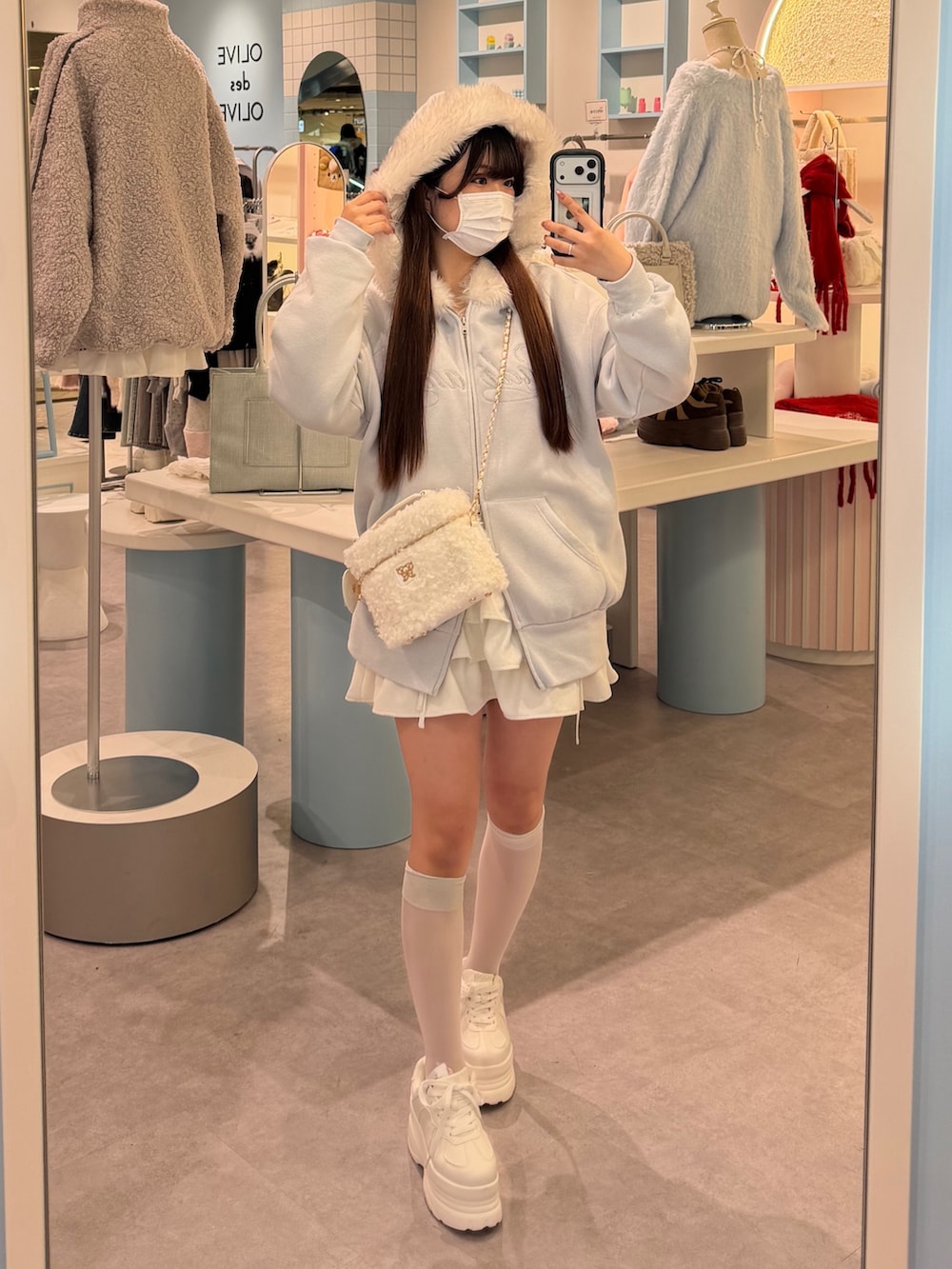 ブルー系のパーカー、ホワイト系のショルダーバッグ、ホワイト系のスカートを着用したレディースの冬コーディネートの2枚目の写真