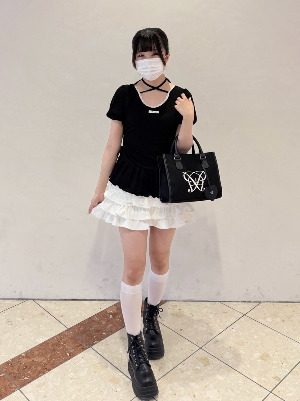 ブラック系のTシャツ/カットソー、ホワイト系のスカート、ブラック系のトートバッグを着用したレディースの春コーディネートの5枚目の写真