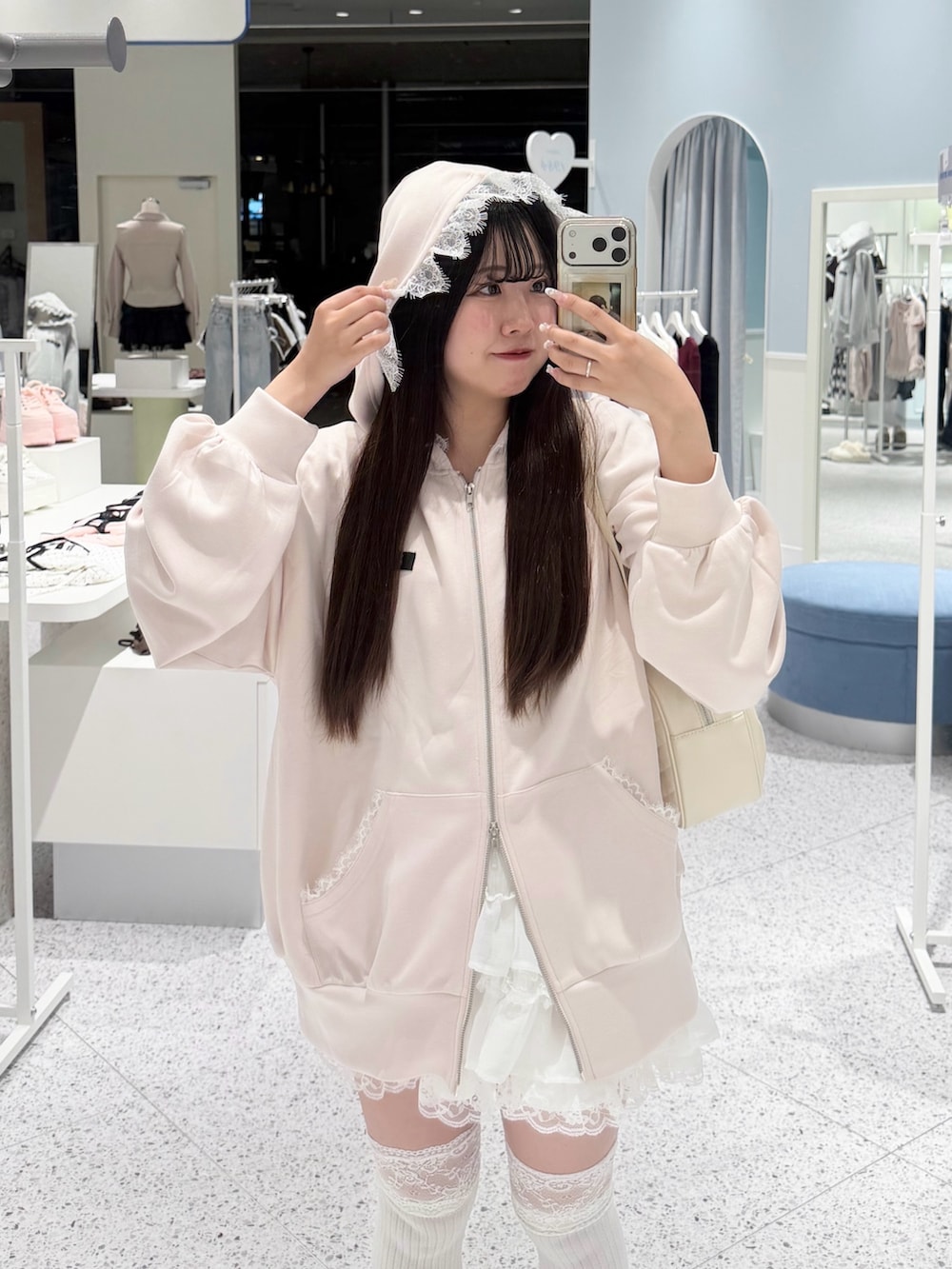 ピンク系のパーカー、ホワイト系のスカート、ホワイト系のボストンバッグを着用したレディースの秋コーディネートの2枚目の写真