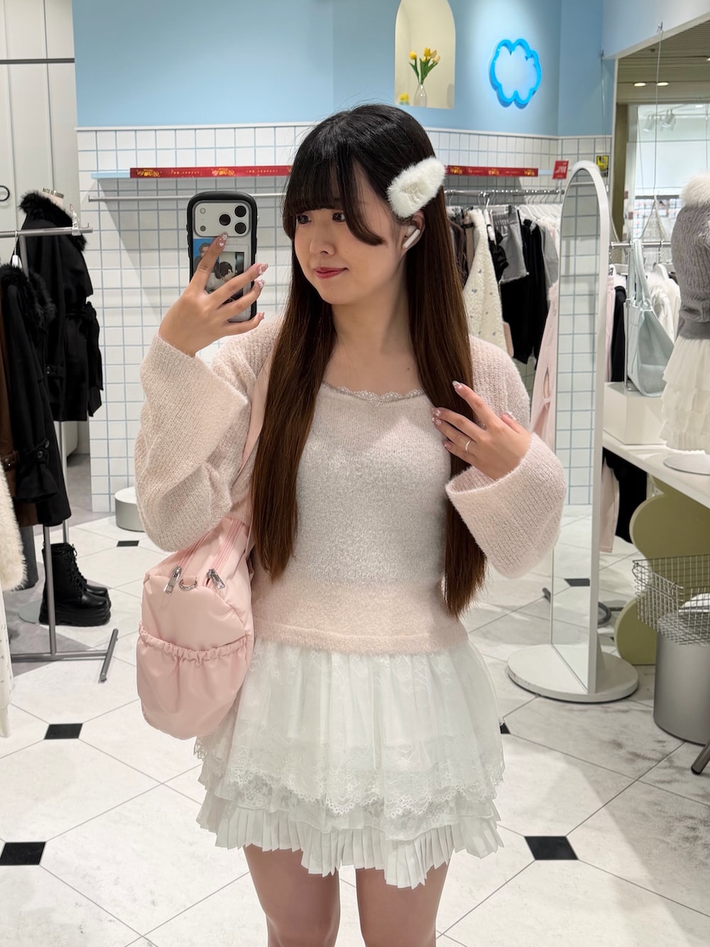 ピンク系のアンサンブル、ホワイト系のスカート、ピンク系のボストンバッグを着用したレディースの冬コーディネートの2枚目の写真