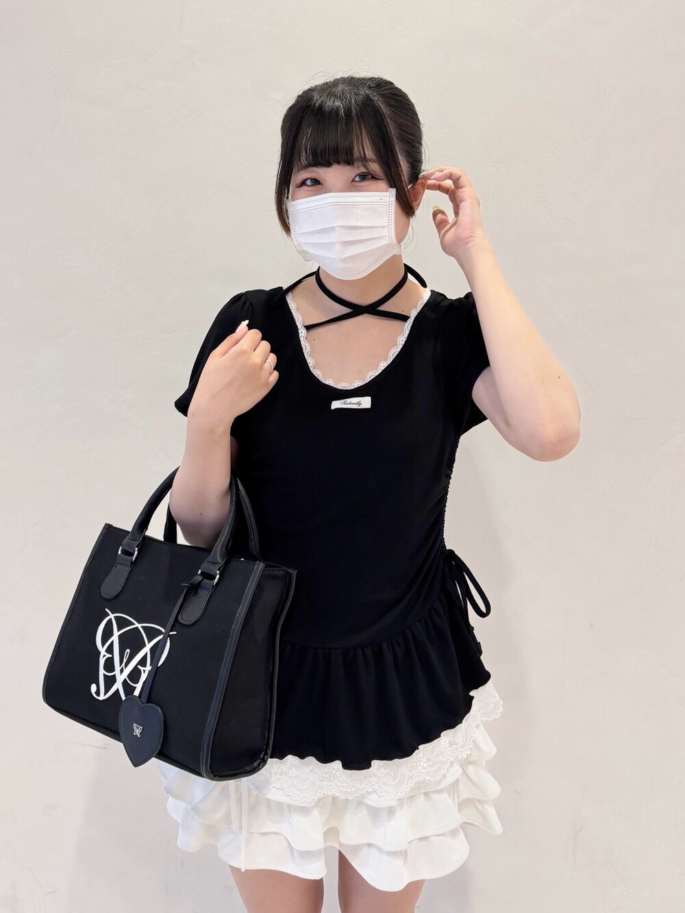 ブラック系のTシャツ/カットソー、ホワイト系のスカート、ブラック系のトートバッグを着用したレディースの春コーディネートの4枚目の写真