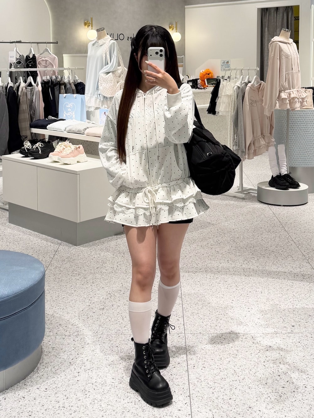 ホワイト系のパーカー、ブラック系のスカート、ブラック系のボストンバッグを着用したレディースの春コーディネートの5枚目の写真