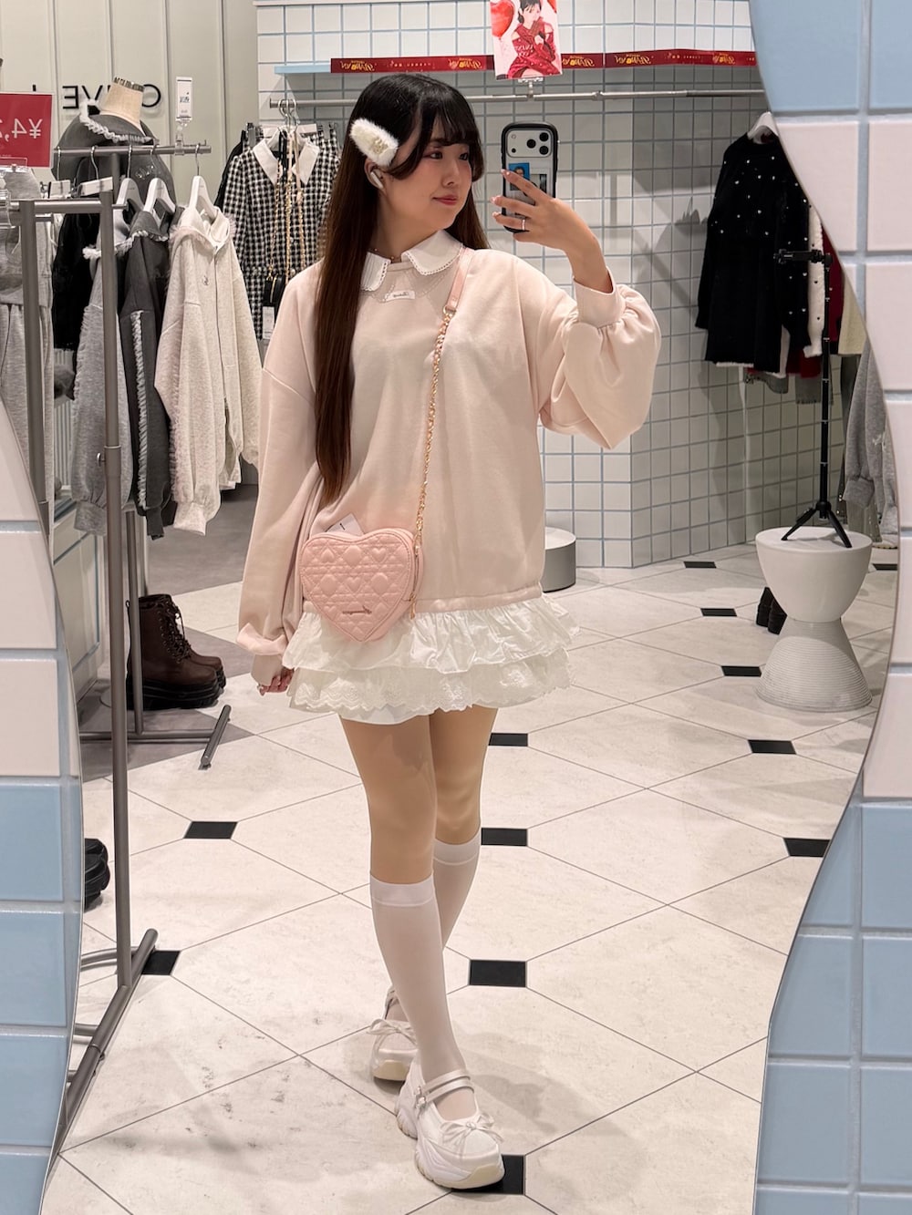 ピンク系のスウェット、ピンク系のショルダーバッグ、ホワイト系のスニーカーを着用したレディースの冬コーディネートの4枚目の写真