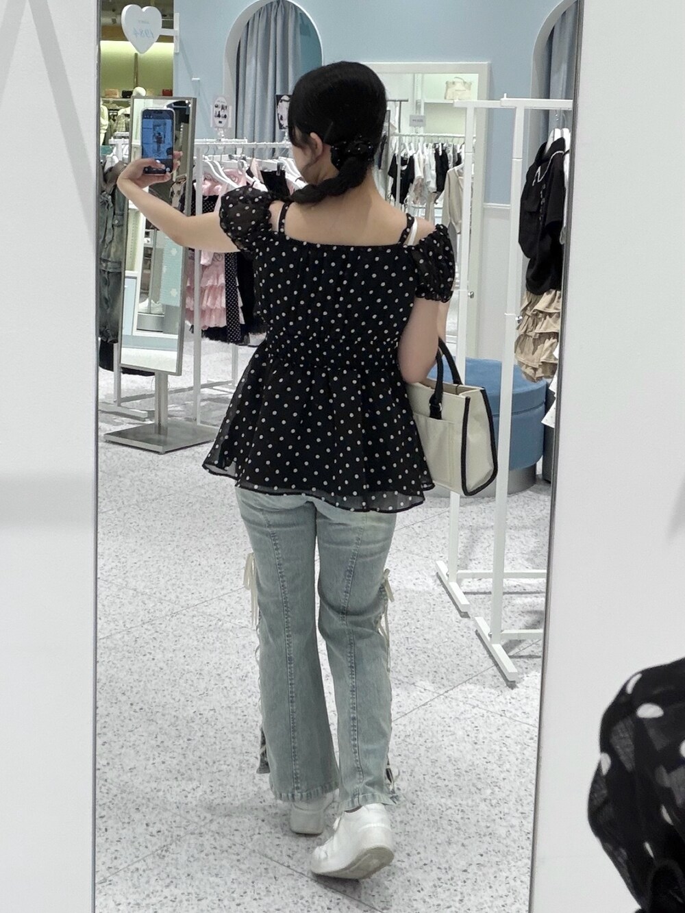 ブラック系のチュニック、ブルー系のデニムパンツ、ホワイト系のトートバッグを着用したレディースの春コーディネートの3枚目の写真