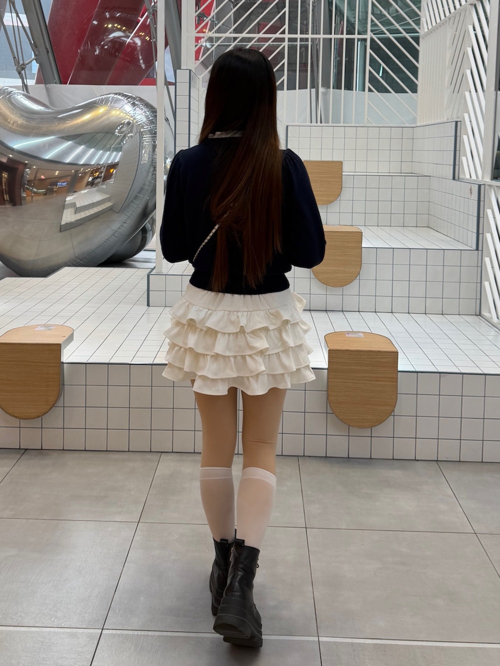 ブルー系のニット/セーター、ホワイト系のスカート、ホワイト系のハンドバッグを着用したレディースの冬コーディネートの4枚目の写真