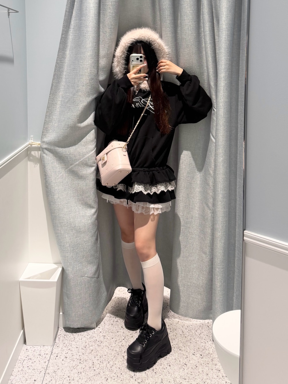 ブラック系のパーカー、ホワイト系のスカート、ピンク系のショルダーバッグを着用したレディースの秋コーディネートの3枚目の写真