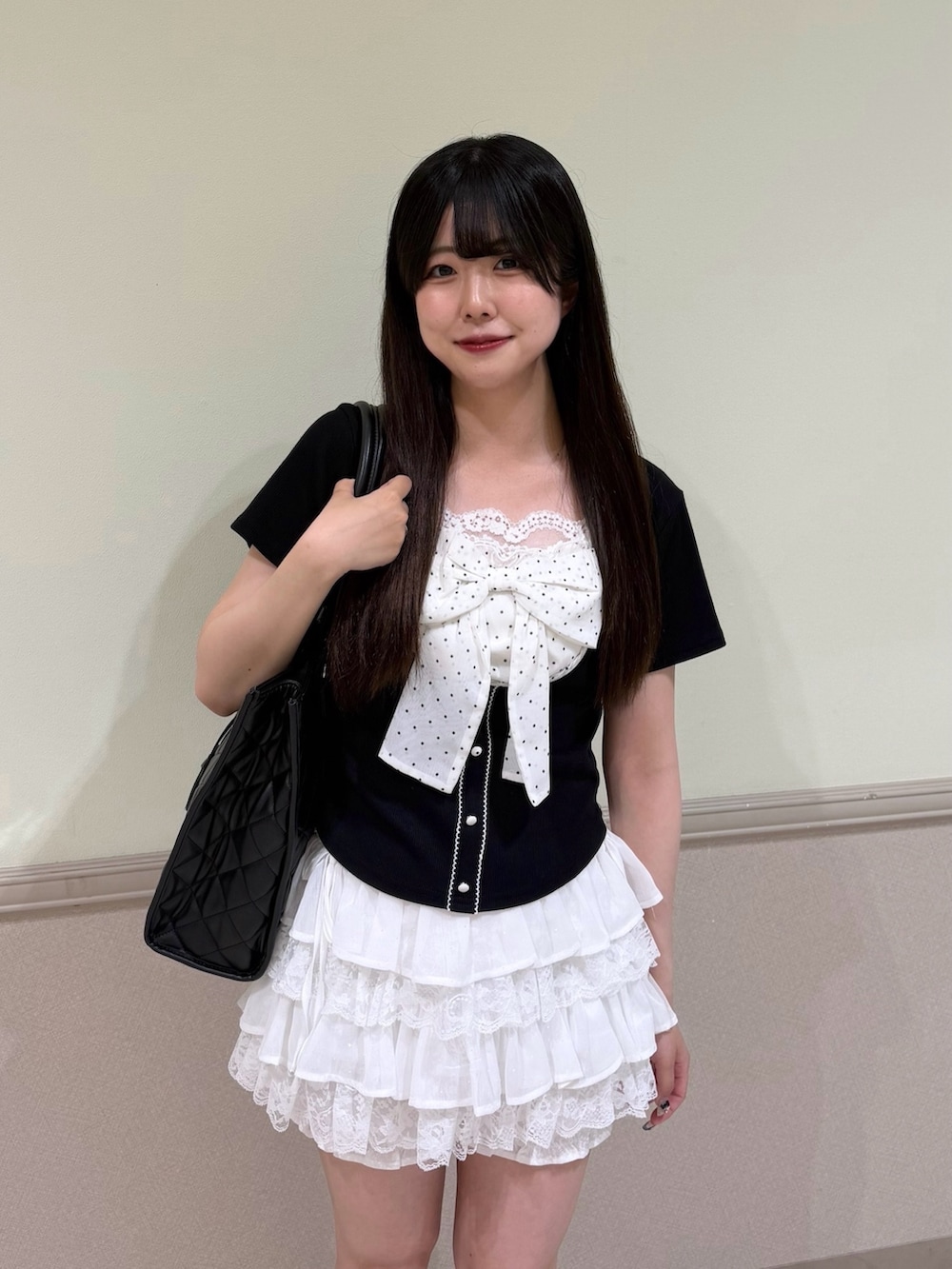 ブラック系のTシャツ/カットソー、ホワイト系のスカート、ブラック系のトートバッグを着用したレディースの夏コーディネートの2枚目の写真