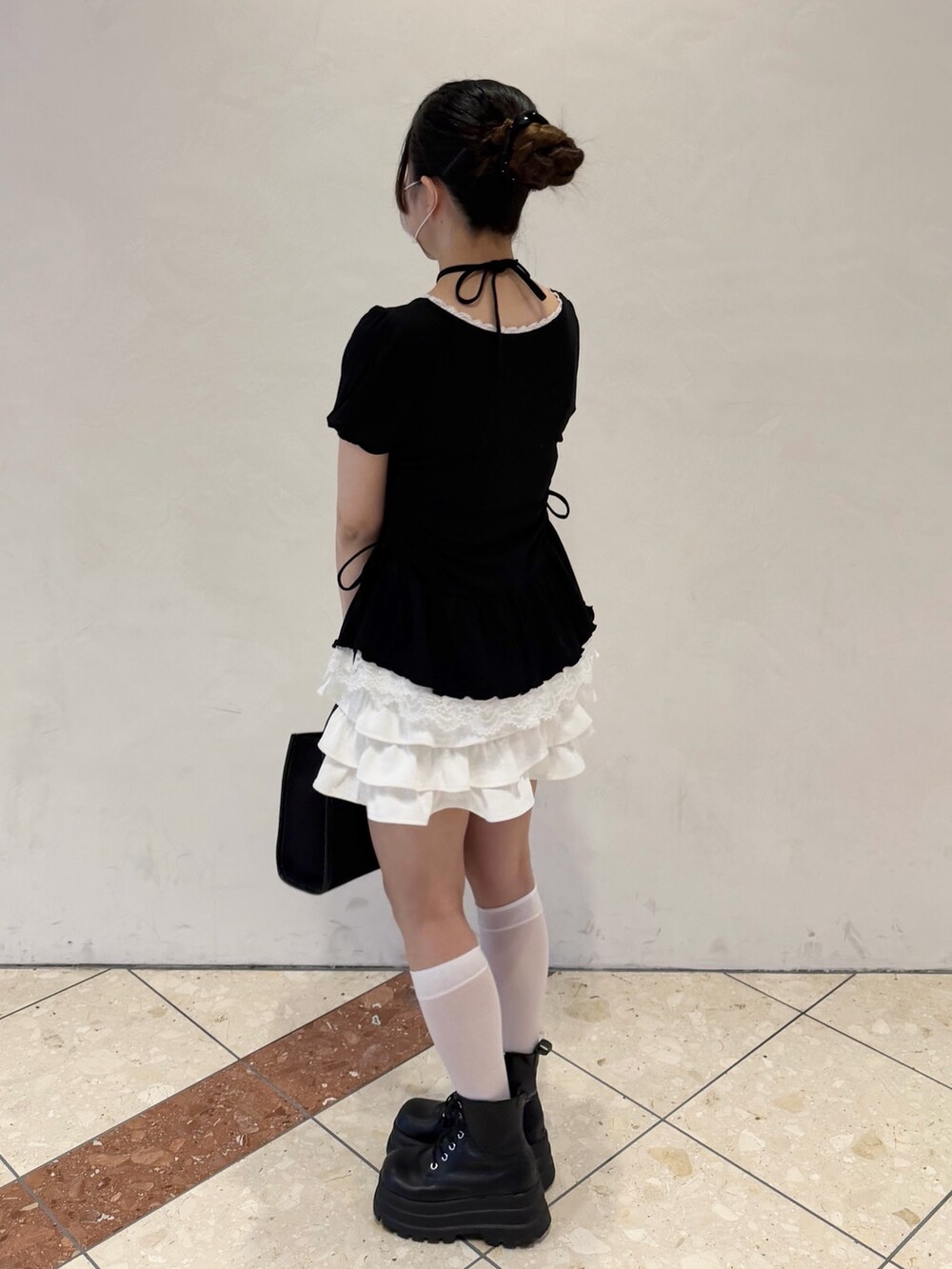 ブラック系のTシャツ/カットソー、ホワイト系のスカート、ブラック系のトートバッグを着用したレディースの春コーディネートの3枚目の写真