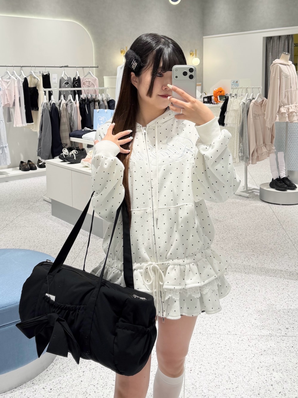 ホワイト系のパーカー、ブラック系のスカート、ブラック系のボストンバッグを着用したレディースの春コーディネートの3枚目の写真