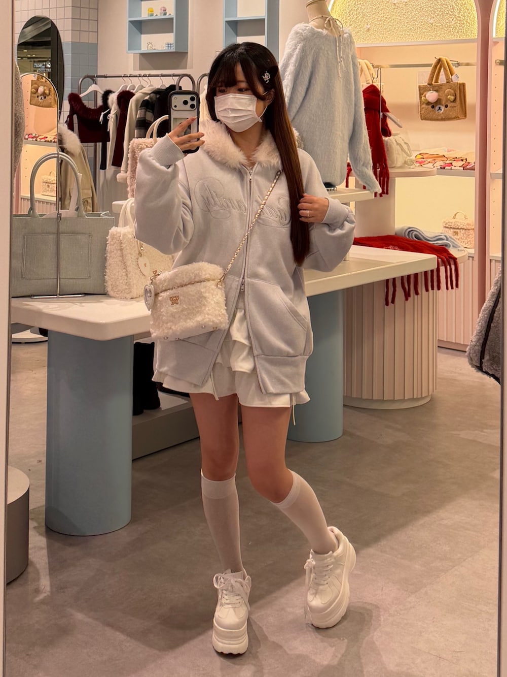 ブルー系のパーカー、ホワイト系のショルダーバッグ、ホワイト系のスカートを着用したレディースの冬コーディネートの5枚目の写真