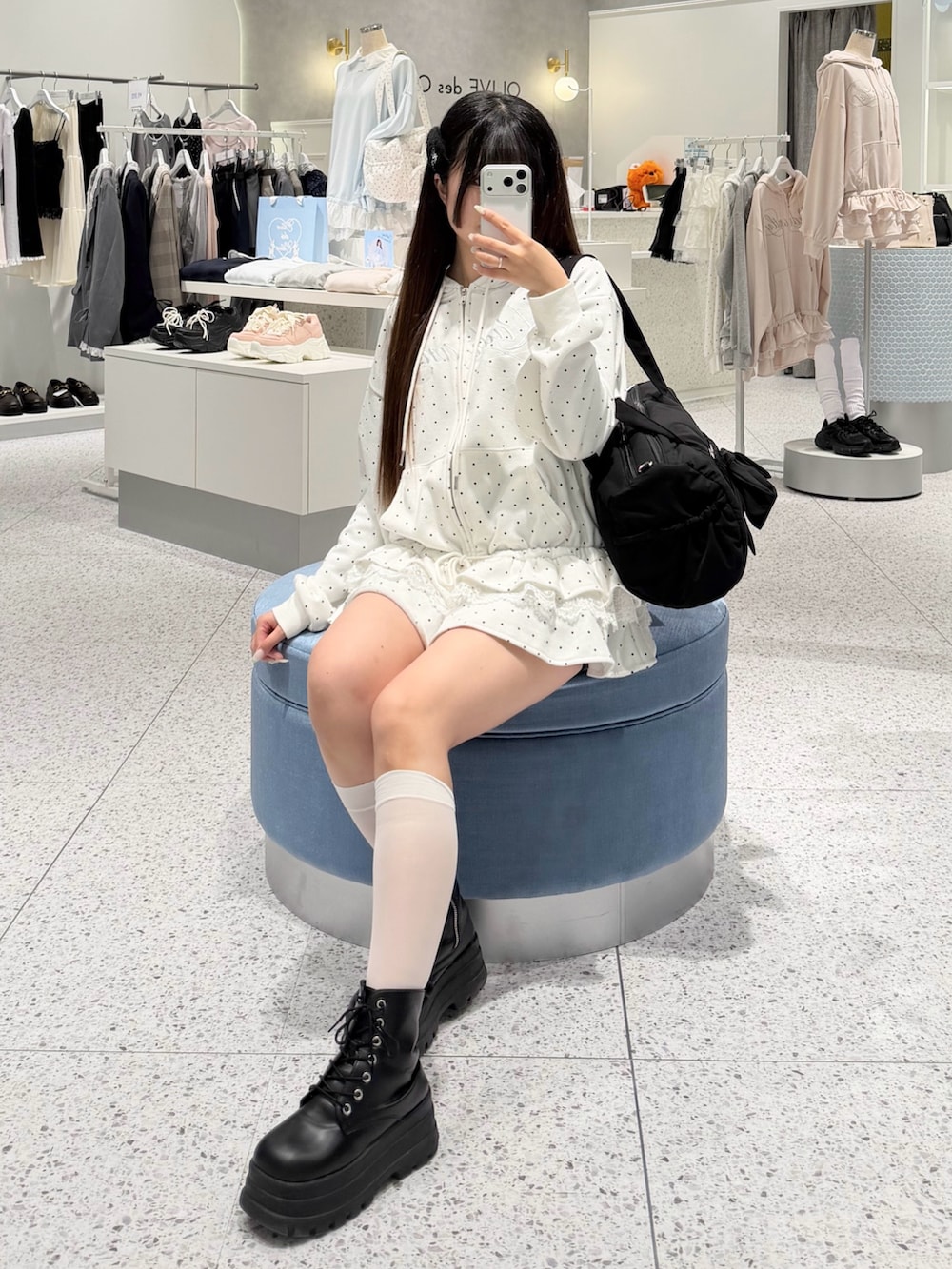 ホワイト系のパーカー、ブラック系のスカート、ブラック系のボストンバッグを着用したレディースの春コーディネートの4枚目の写真