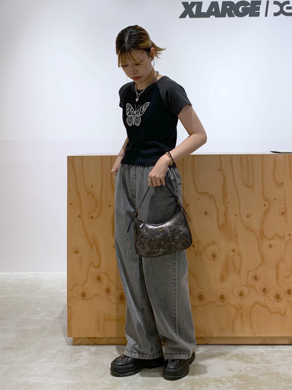 ブラック系のデニムパンツ、ゴールド系のハンドバッグ、ブラック系のTシャツ/カットソーを着用したレディースの夏コーディネートの2枚目の写真