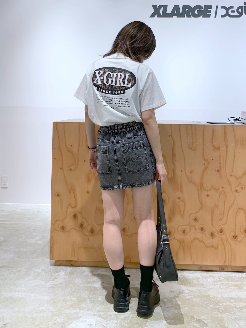 ブラック系のデニムジャケット、ブラック系のデニムスカート、ブラック系のハンドバッグを着用したレディースの夏コーディネートの4枚目の写真