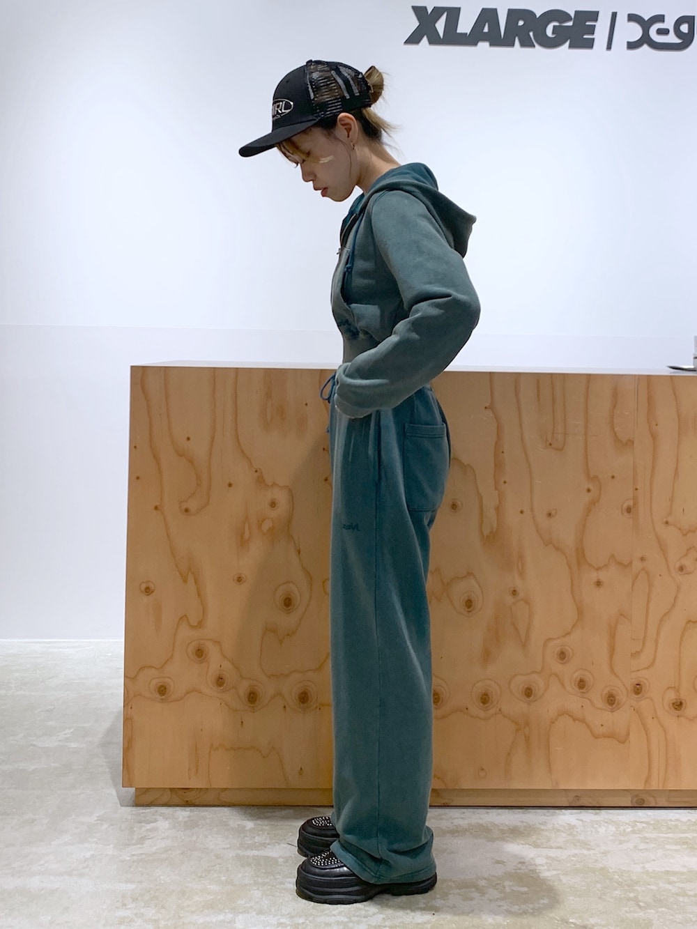 グリーン系のスウェットパンツ、グリーン系のパーカー、ブラック系のキャップを着用したレディースの夏コーディネートの2枚目の写真