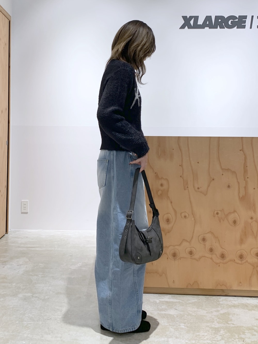 ブラック系のニット/セーター、ブルー系のデニムパンツ、ブラック系のハンドバッグを着用したレディースの冬コーディネートの2枚目の写真