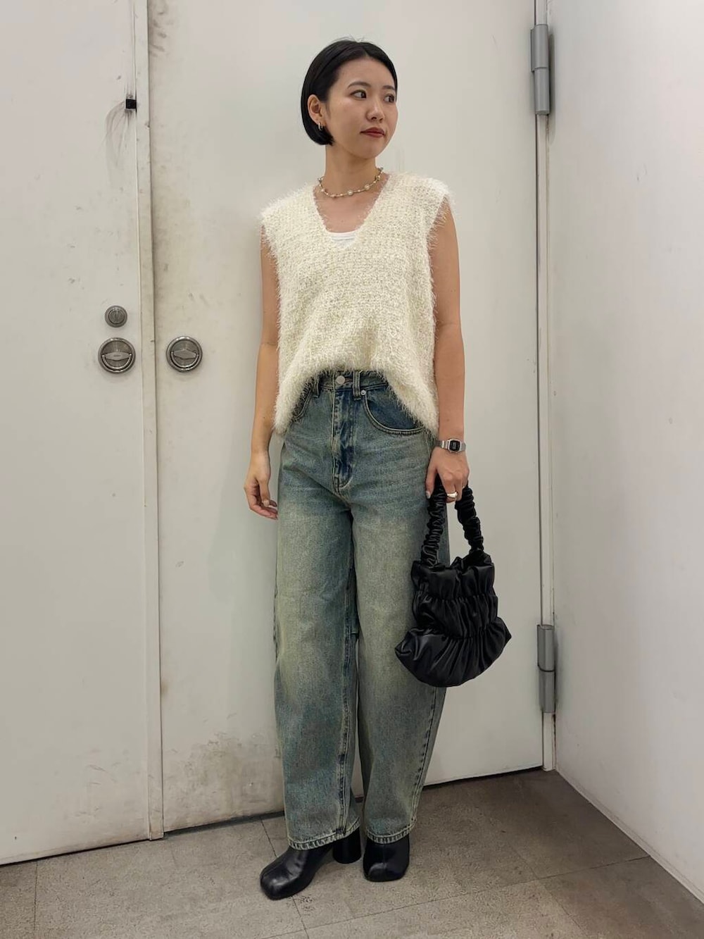 ブラック系のその他シューズ、ブラック系のハンドバッグ、ブルー系のデニムパンツを着用したレディースの秋コーディネートの3枚目の写真