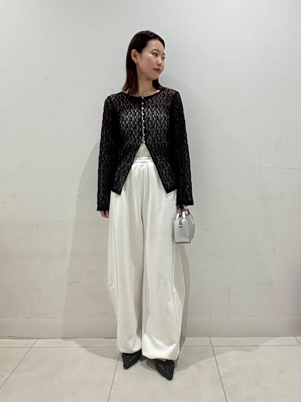 シルバー系のハンドバッグ、ホワイト系のキャミソール、ブラック系のサンダルを着用したレディースの夏コーディネートの3枚目の写真