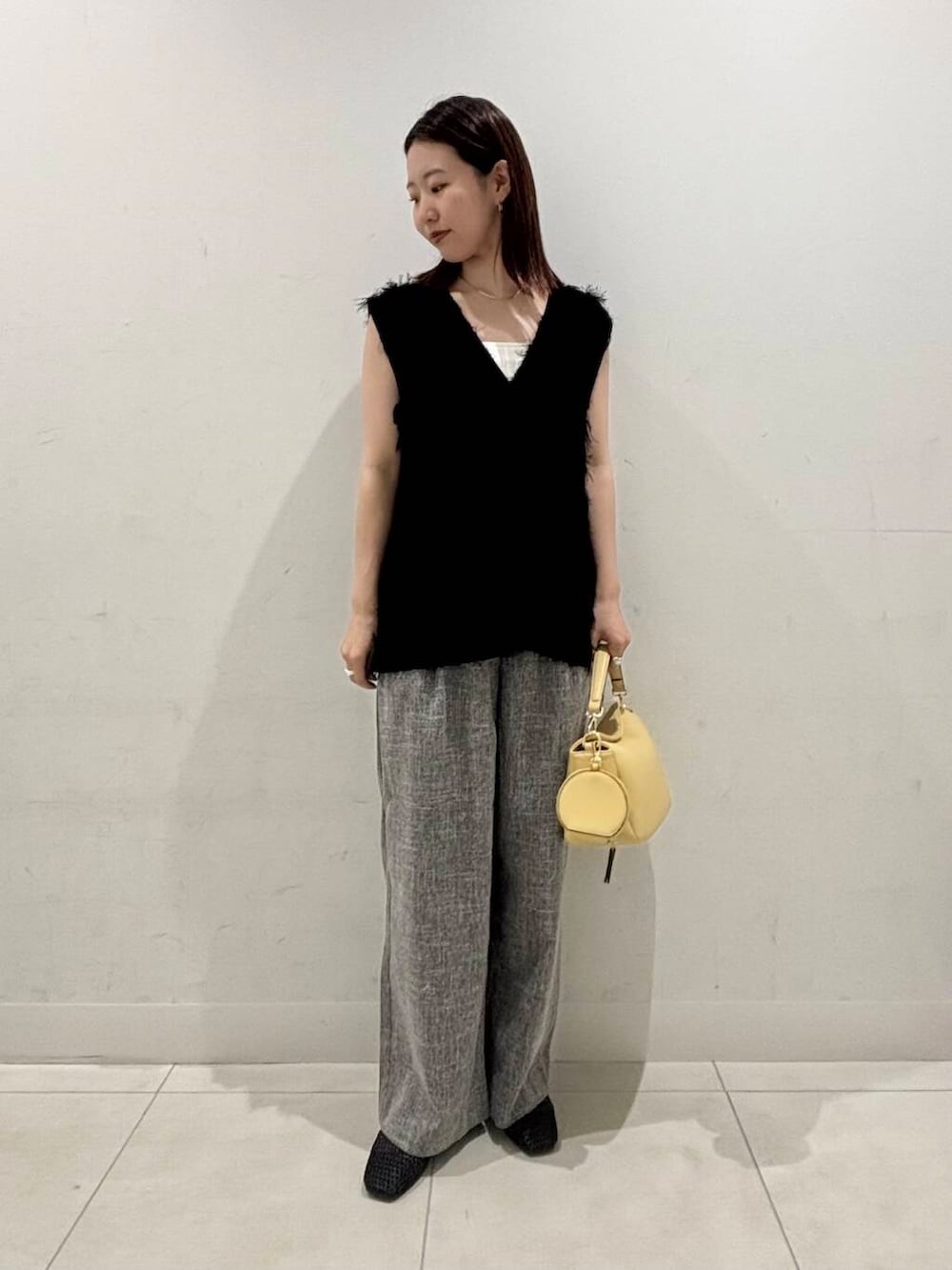 イエロー系のショルダーバッグ、ホワイト系のキャミソール、ブラック系のバレエシューズを着用したレディースの夏コーディネートの2枚目の写真