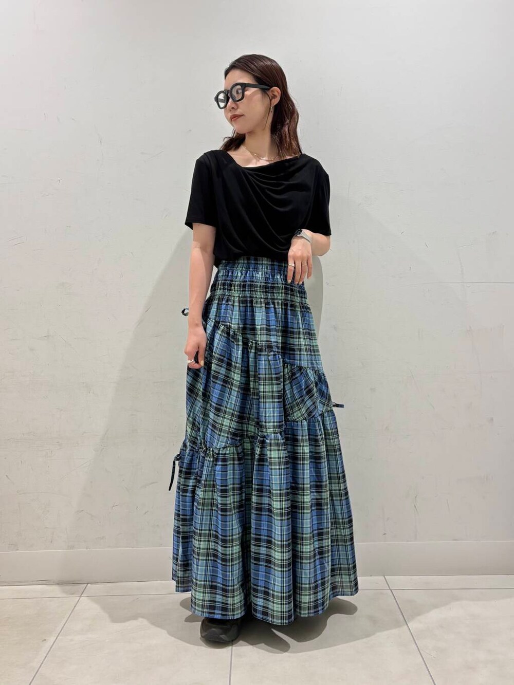 ブルー系のスカート、ブラック系のTシャツ/カットソー、ブラック系のメガネを着用したレディースの夏コーディネートの3枚目の写真