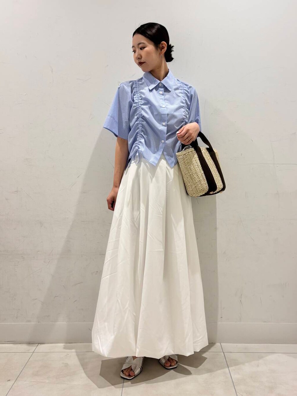 ホワイト系のハンドバッグ、ホワイト系のスカート、シルバー系のサンダルを着用したレディースの春コーディネートの3枚目の写真