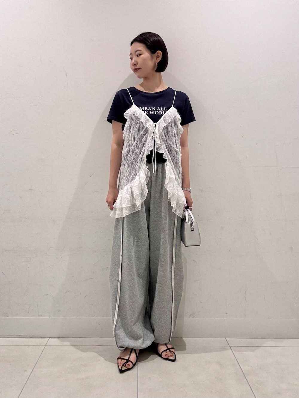 シルバー系のハンドバッグ、ブラック系のサンダル、その他のTシャツ/カットソーを着用したレディースの夏コーディネートの3枚目の写真