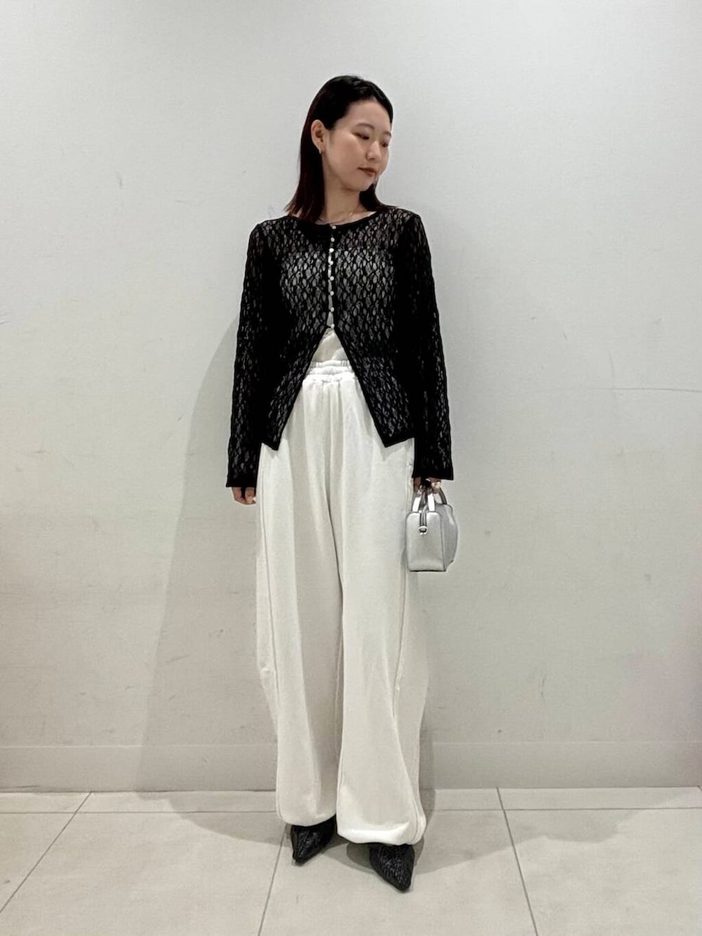 シルバー系のハンドバッグ、ホワイト系のキャミソール、ブラック系のサンダルを着用したレディースの夏コーディネートの2枚目の写真