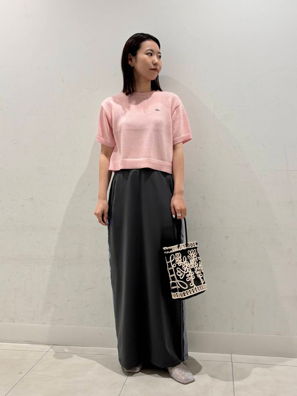 ブラック系のショルダーバッグ、シルバー系のパンプス、グレー系のスカートを着用したレディースの春コーディネートの2枚目の写真