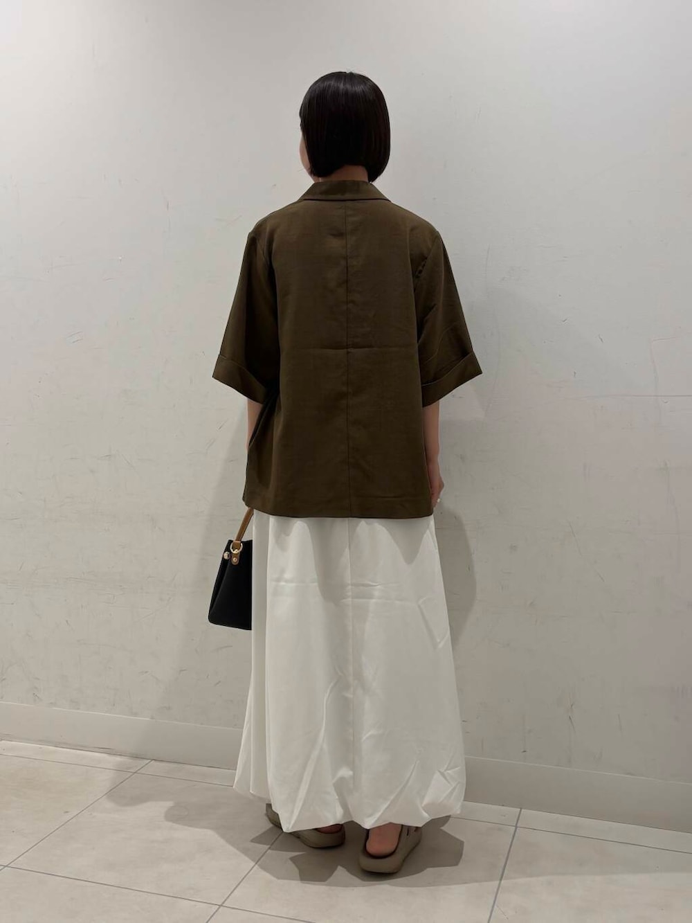 ブラック系のトートバッグ、ホワイト系のスカート、ベージュ系のサンダルを着用したレディースの夏コーディネートの4枚目の写真