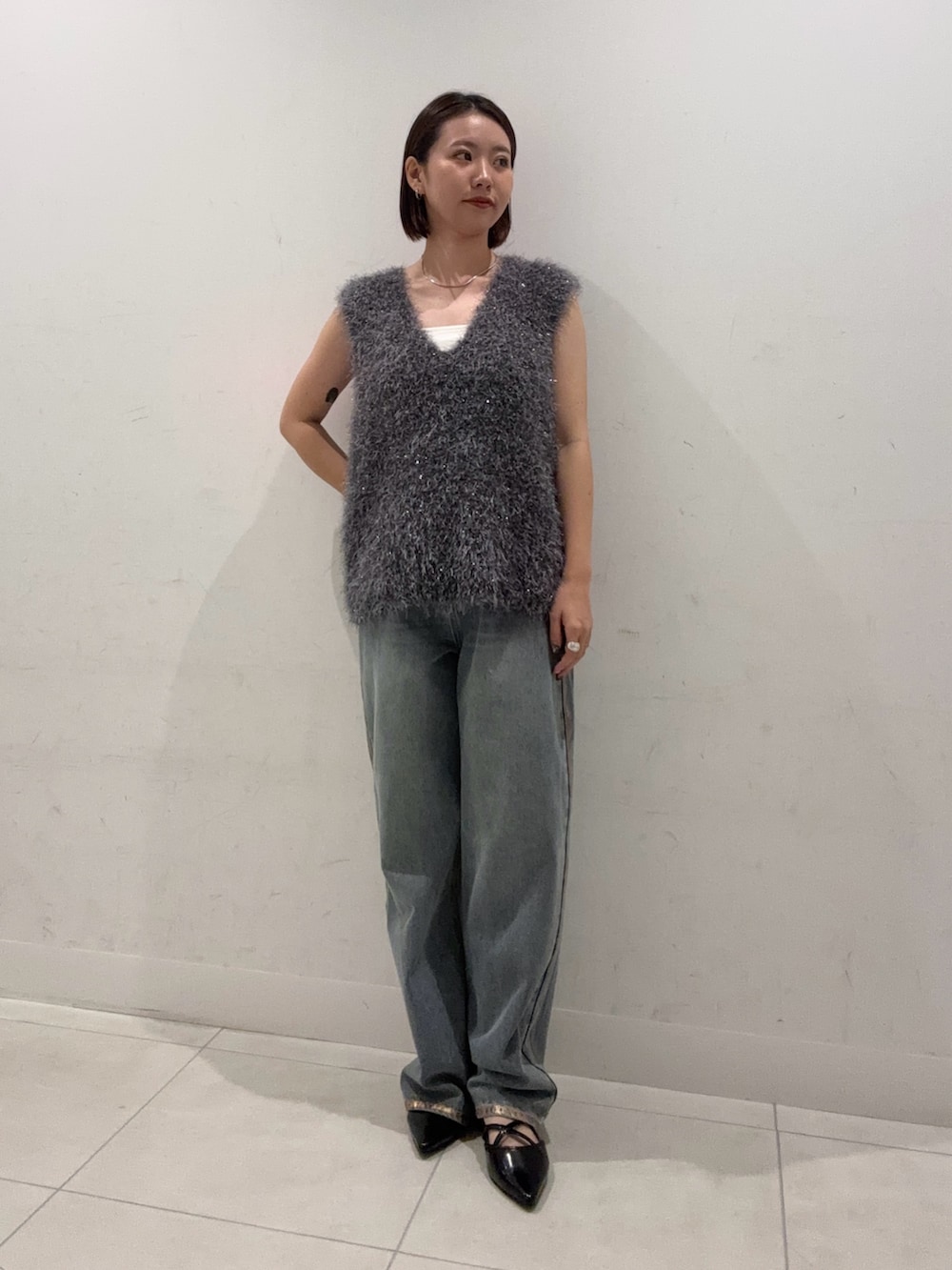 グレー系のベスト、ホワイト系のキャミソール、ブルー系のデニムパンツを着用したレディースの夏コーディネートの3枚目の写真