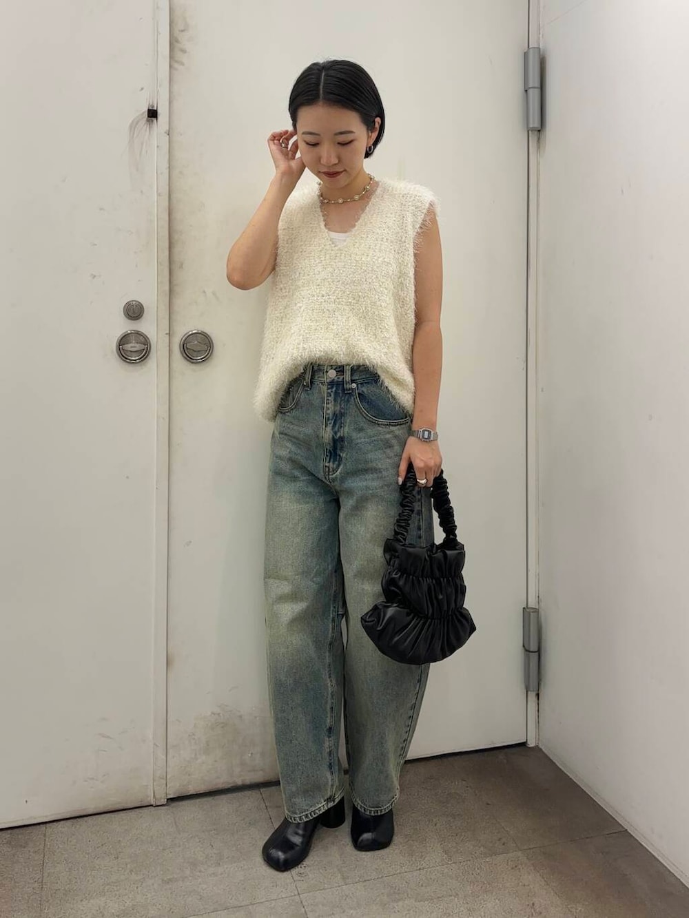 ブラック系のその他シューズ、ブラック系のハンドバッグ、ブルー系のデニムパンツを着用したレディースの秋コーディネートの2枚目の写真