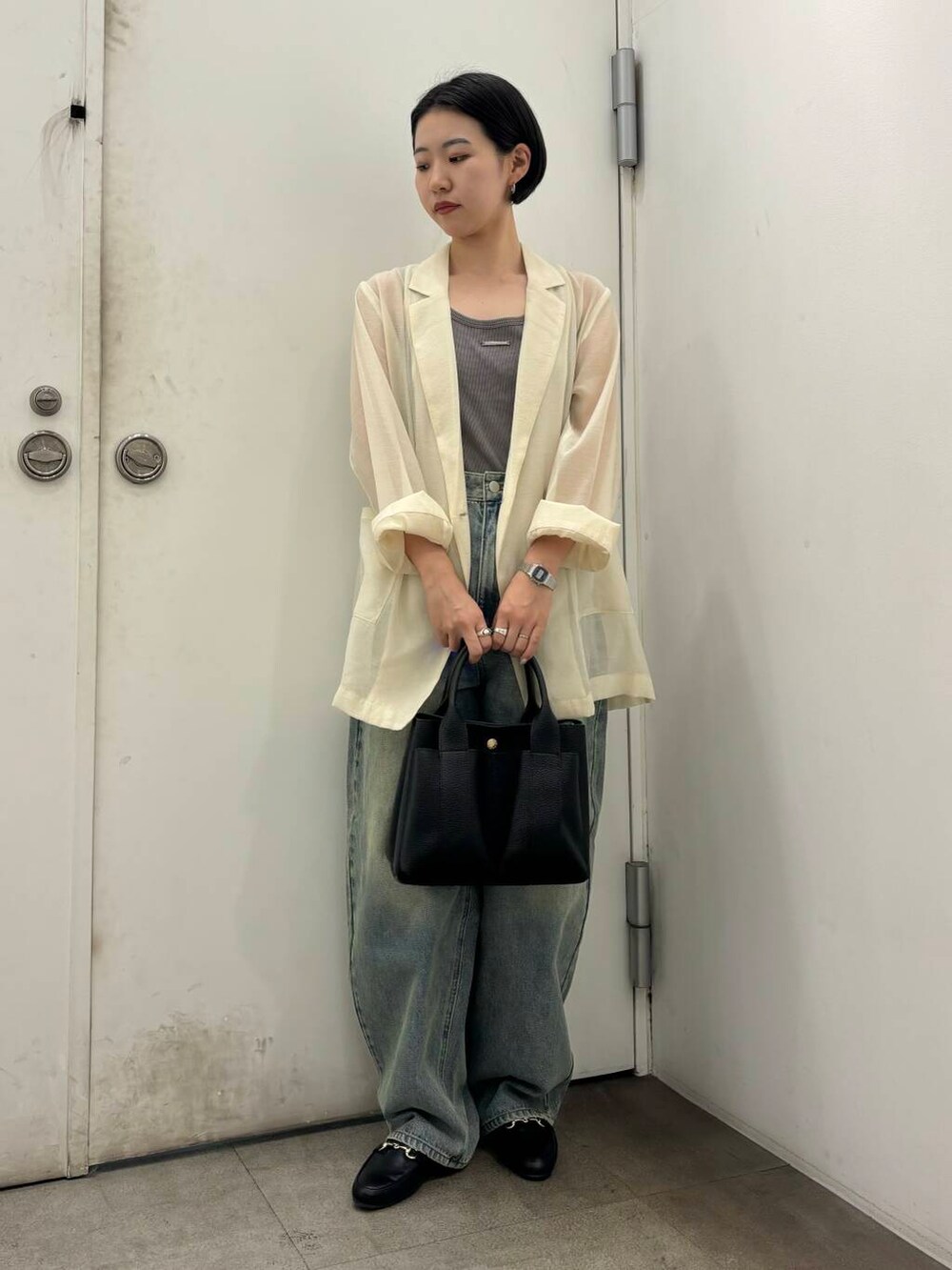 ブラック系のローファー、ブラック系のトートバッグ、ブルー系のデニムパンツを着用したレディースの秋コーディネートの2枚目の写真