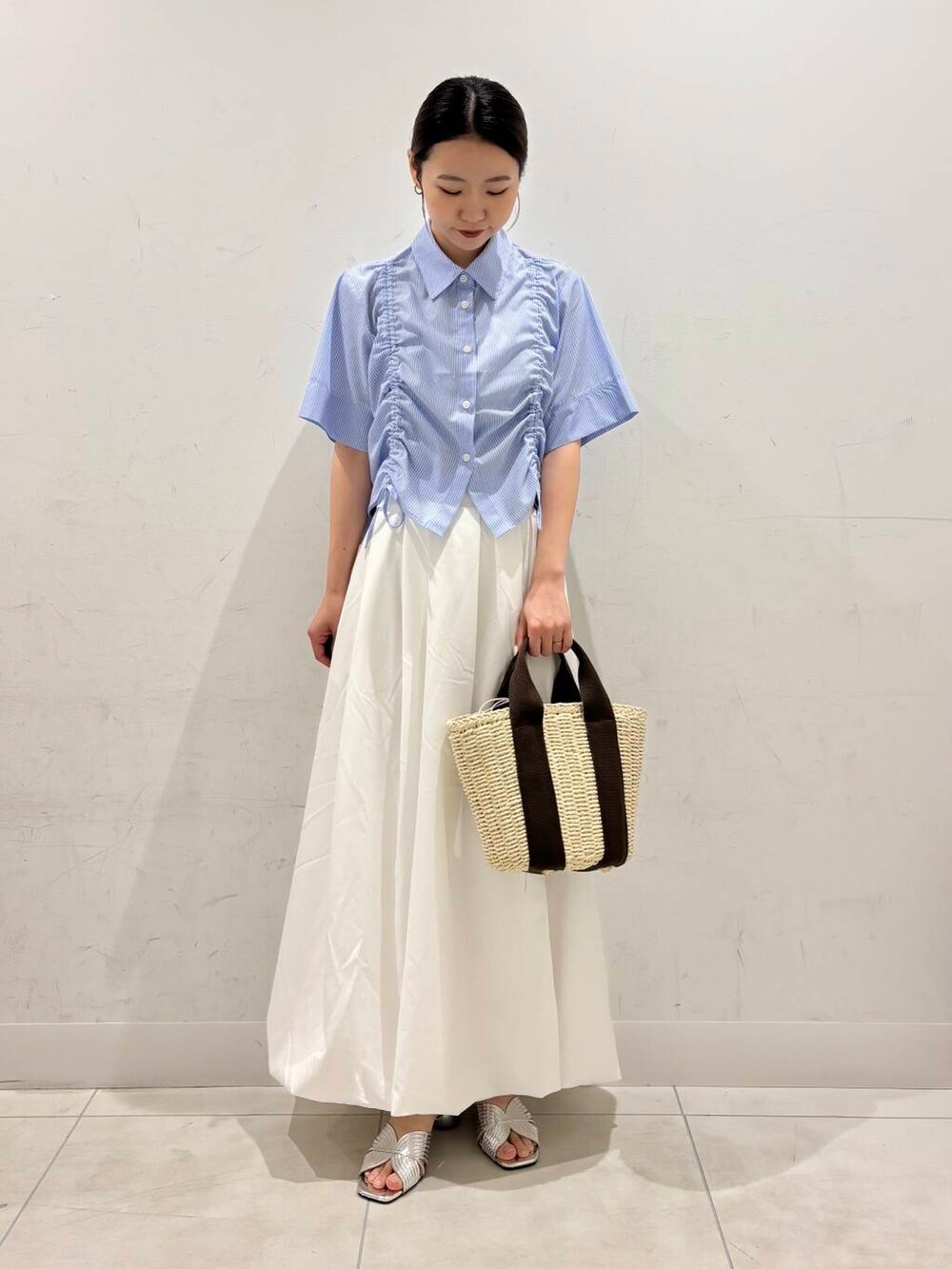 ホワイト系のハンドバッグ、ホワイト系のスカート、シルバー系のサンダルを着用したレディースの春コーディネートの2枚目の写真