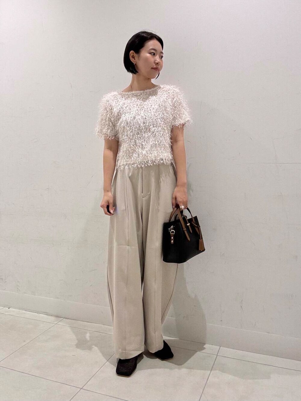 ブラック系のハンドバッグ、ブラック系のその他シューズ、ホワイト系のTシャツ/カットソーを着用したレディースの夏コーディネートの2枚目の写真