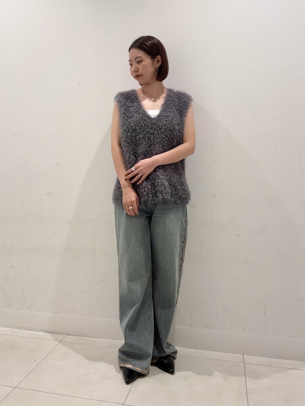 グレー系のベスト、ホワイト系のキャミソール、ブルー系のデニムパンツを着用したレディースの夏コーディネートの2枚目の写真