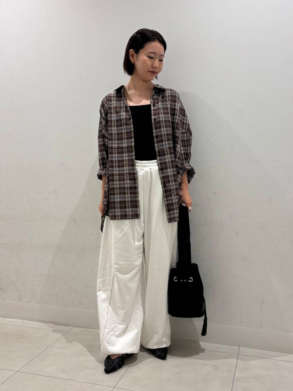 ブラック系のキャミソール、ブラック系のサンダル、ホワイト系のスウェットパンツを着用したレディースの夏コーディネートの3枚目の写真