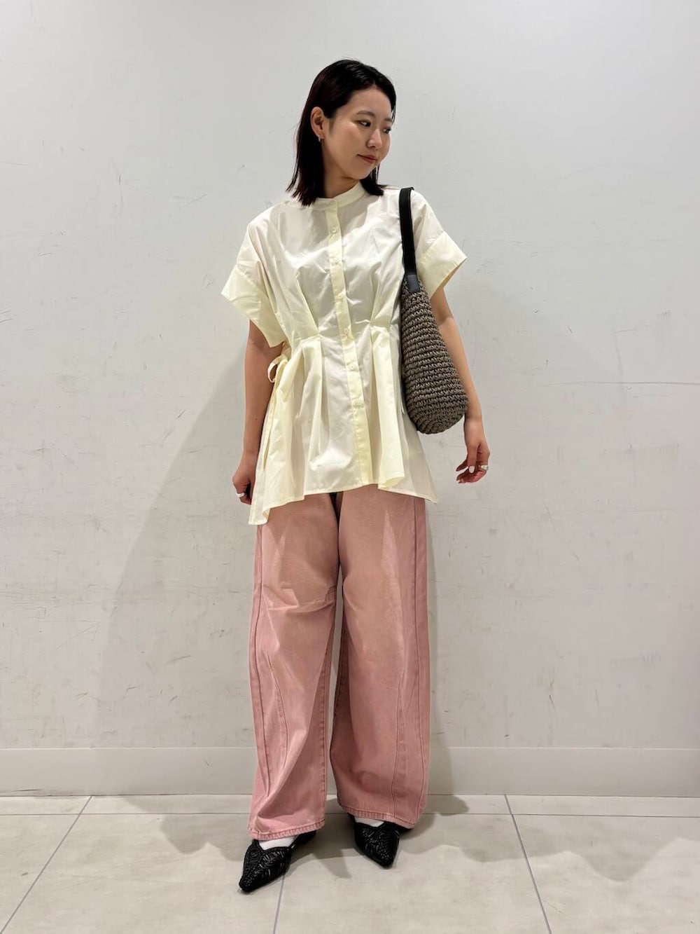 グレー系のトートバッグ、ブラック系のサンダル、ピンク系のデニムパンツを着用したレディースの春コーディネートの2枚目の写真