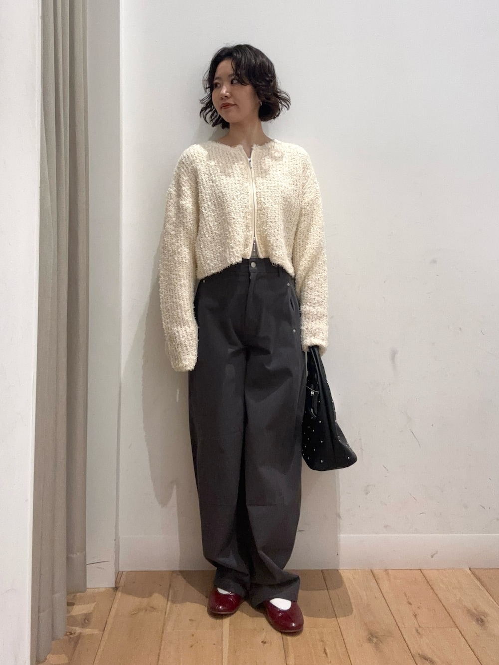 ホワイト系のカーディガン/ボレロ、グレー系のその他パンツ、ブラック系のハンドバッグを着用したレディースの冬コーディネートの2枚目の写真