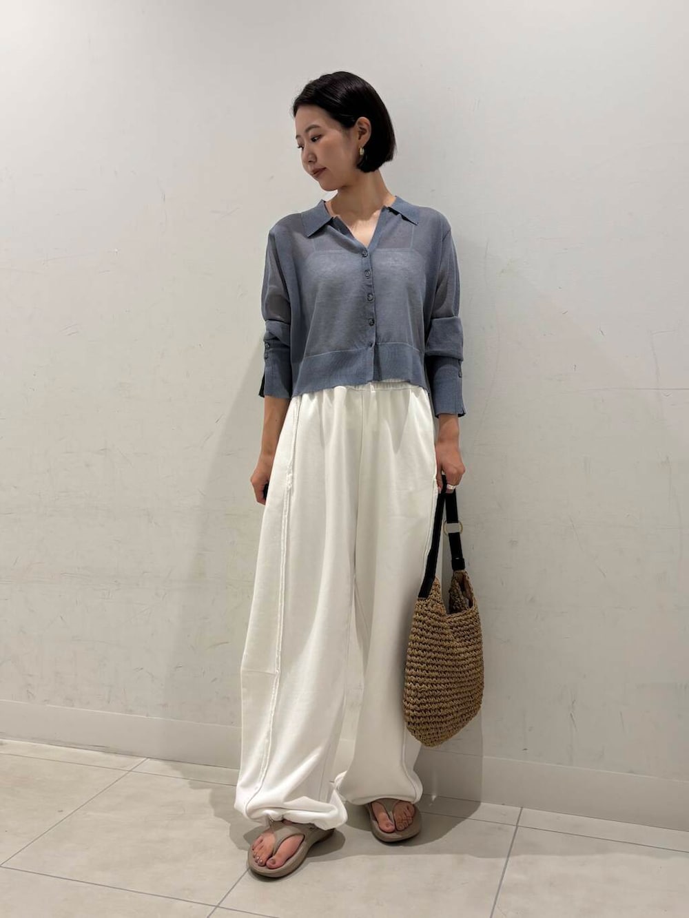 イエロー系のトートバッグ、ベージュ系のサンダル、ホワイト系のキャミソールを着用したレディースの夏コーディネートの3枚目の写真