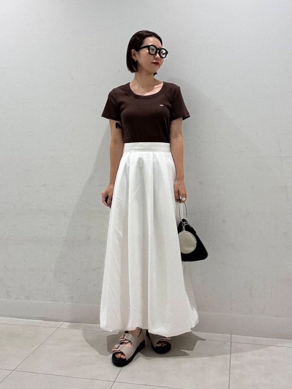 ホワイト系のスカート、ブラック系のハンドバッグ、グレー系のサンダルを着用したレディースの夏コーディネートの3枚目の写真