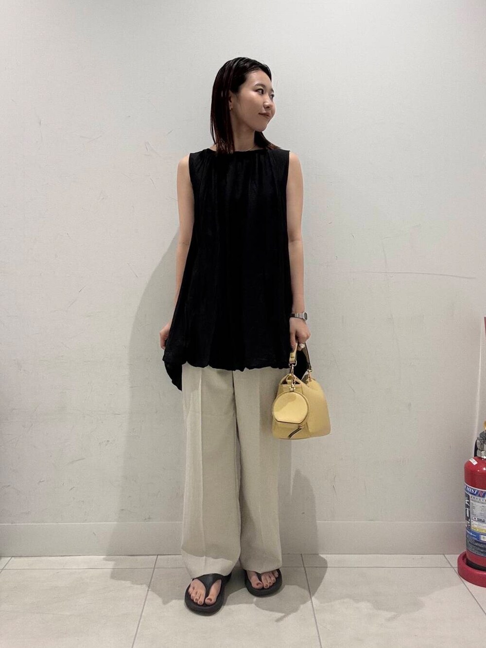 イエロー系のショルダーバッグ、ベージュ系のその他パンツ、ブラック系のシャツ/ブラウスを着用したレディースの春コーディネートの3枚目の写真