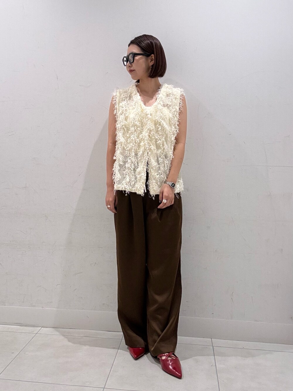 ホワイト系のベスト、ブラウン系のその他パンツ、レッド系のその他シューズを着用したレディースの夏コーディネートの2枚目の写真